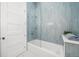 Bathroom featuring blue tiled shower with glass door, white tub, and modern fixtures at 1400 Nottingham St, Orlando, FL 32803