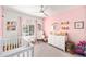 Charming Bedroom featuring a crib, rocker, and pink accent wall at 1415 Sherbourne St, Winter Garden, FL 34787