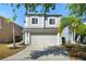 Light-gray home featuring manicured lawn with curb appeal, palm trees, and a two-car garage at 1415 Sherbourne St, Winter Garden, FL 34787