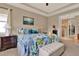 Bright bedroom showcases a floral bedspread, tray ceilings, and ensuite bathroom with walk in closet at 1424 Palisades Lane, Deland, FL 32724