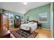 A green-walled bedroom featuring a bed, hardwood floors, two windows, and vintage furniture at 14315 Hampshire Bay Cir, Winter Garden, FL 34787
