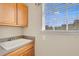 Bright laundry room features a utility sink, wood cabinets, and a window at 14315 Hampshire Bay Cir, Winter Garden, FL 34787