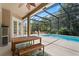 Covered patio with a wooden table and bench overlooking the private screened-in pool and backyard at 14315 Hampshire Bay Cir, Winter Garden, FL 34787