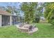Outdoor fire pit with stone surround, surrounded by 5 comfortable Adirondack chairs in lush backyard at 1518 Shadowmoss Cir, Lake Mary, FL 32746