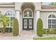 Elegant front entrance featuring a decorative glass double door, arched entryway, and manicured landscaping at 1518 Shadowmoss Cir, Lake Mary, FL 32746
