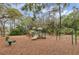 Community playground featuring slides, swings, and climbing structures surrounded by trees and wood mulch at 1518 Shadowmoss Cir, Lake Mary, FL 32746