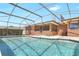 Backyard pool with screened enclosure next to brick house and green shrubs at 2102 E Atmore Cir, Deltona, FL 32725