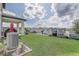 Spacious backyard with green lawn, covered patio, and views of neighboring houses and treeline at 2412 Gold Dust Dr, Clermont, FL 34715