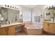 Bright bathroom featuring a large soaking tub, double vanities, and modern lighting fixtures at 2515 Wekiva Walk Way, Apopka, FL 32703