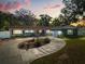 Charming single story home with an inviting circular driveway and lush landscaping at dusk at 2945 Southgate Ter, Orlando, FL 32818