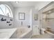 Bright bathroom features a soaking tub beneath an arched window and a glass-enclosed walk-in shower at 3150 Sawgrass Ct, Kissimmee, FL 34746