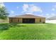 Rear view of a well-manicured lawn, with view of the home's screened lanai and exterior windows at 3281 Pawleys N Loop, St Cloud, FL 34769