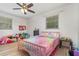 Bright bedroom with a ceiling fan and two windows, featuring a pink bed and hardwood floors at 360 Westchester Dr, Deland, FL 32724