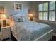 Bedroom with white shuttered window, white furniture, lamps, and a bed with teal pattern bedding at 3609 Azurite Ct, Deland, FL 32724