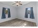 Cozy bedroom with wood-look flooring, two windows with drapes, and light walls at 451 Hibiscus Rd, Casselberry, FL 32707