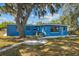 Bright blue home exterior with a manicured lawn and mature tree in a sunny, serene setting at 451 Hibiscus Rd, Casselberry, FL 32707