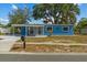 Charming single-story blue home featuring a covered carport and well-maintained landscaping at 451 Hibiscus Rd, Casselberry, FL 32707