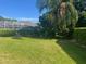 Serene backyard with well-manicured lawn, privacy hedge, and a view of the screened-in pool enclosure at 702 Palenci Ct, Winter Springs, FL 32708