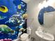 Quaint half-bath featuring ocean-themed wallpaper, rounded mirror and sink, and modern toilet at 8961 Rhodes St, Kissimmee, FL 34747