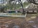 Charming single-story home featuring mature trees, a white picket fence, and a covered parking area at 9741 Se Highway 464C Se Hwy, Ocklawaha, FL 32179