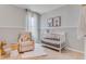 Charming Bedroom with a crib, comfortable chair, neutral tones, and soft, natural light at 11148 Amber Ridge Dr, Zellwood, FL 32798