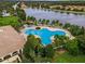 Aerial view of a clover-shaped pool surrounded by palm trees, lounge chairs, and overlooking a lake at 11763 Eagle Ray Ln, Orlando, FL 32827