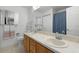 Bright bathroom featuring double sinks, wooden cabinets, and shower curtain at 16692 Lake Pickett Rd, Orlando, FL 32820