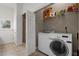 Functional laundry room with front load washer/dryer, wire shelving, tile floors, and nearby shower stall at 16692 Lake Pickett Rd, Orlando, FL 32820