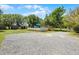 Above ground pool with wood deck, turquoise umbrella, surrounded by grassy yard and gravel driveway at 16692 Lake Pickett Rd, Orlando, FL 32820
