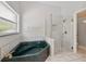 Bathroom features a green corner bathtub and glass shower with grey and white tile accents and a window at 1851 Sweetwater West Cir, Apopka, FL 32712