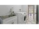 Laundry room boasts stainless sink, white cabinets, and modern washer and dryer at 1851 Sweetwater West Cir, Apopka, FL 32712