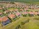 Beautiful aerial view of homes with terracotta roofs in a landscaped community near a lake at 1945 Via Lago Dr, Lakeland, FL 33810