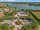 An aerial view of the community featuring a lake, clubhouse, and pool with a roundabout entrance and lush landscaping at 1945 Via Lago Dr, Lakeland, FL 33810