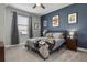 This bedroom features gray carpet, blue accent wall, ceiling fan, window with grey curtains at 1945 Via Lago Dr, Lakeland, FL 33810