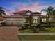 Beautiful home with a tile roof, brick driveway and tropical landscaping in the front yard at sunset at 1945 Via Lago Dr, Lakeland, FL 33810
