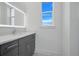 Bathroom features gray vanity with white countertop, illuminated mirror and natural light from window at 3024 Kensington Ave, Davenport, FL 33837
