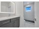 Modern bathroom features a vanity with gray cabinets, lighted mirror, and walk-in shower at 3024 Kensington Ave, Davenport, FL 33837