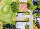 Overhead view of a single-story home with an attached two car garage, near a golf course and a neighborhood street at 32537 Oak Park Dr, Leesburg, FL 34748