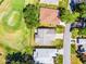Overhead view of a single-story home with an attached two car garage, near a golf course and a neighborhood street at 32537 Oak Park Dr, Leesburg, FL 34748