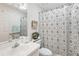 Cozy bathroom with patterned shower curtain and neutral decor, well lit vanity and mirror at 32537 Oak Park Dr, Leesburg, FL 34748