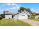 Quaint single-story home with an attached two-car garage, green lawn, and light-blue siding at 32537 Oak Park Dr, Leesburg, FL 34748