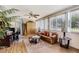 Bright living room with hardwood floors, leather couch, ceiling fan, and large windows at 32537 Oak Park Dr, Leesburg, FL 34748