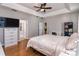 Bedroom with hardwood floors featuring neutral tones, tray ceilings, and ensuite bathroom at 3436 Herringridge Dr, Orlando, FL 32812