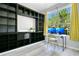 Bright home office equipped with a large built-in shelving unit, dual monitors, and abundant natural light at 8555 Abbotsbury Dr, Windermere, FL 34786