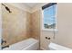 Bathroom featuring a shower and tub combination, neutral colored tile, and a window for natural light at 8565 Tallfield Ave # 1, Orlando, FL 32832