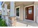 Inviting front porch featuring stacked stone accents, classic columns, and a warm, wood-toned front door at 8565 Tallfield Ave # 1, Orlando, FL 32832