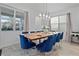 Elegant dining room with a wooden table, blue chairs, natural light, and a stylish chandelier creating a welcoming space at 8953 Amelia Downs Trl, Kissimmee, FL 34747