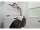 Well-lit laundry room is equipped with modern white machines and wire shelving at 8953 Amelia Downs Trl, Kissimmee, FL 34747