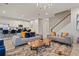 Open-concept living area with a staircase, comfortable sofas, and a view into the modern kitchen with island seating at 8953 Amelia Downs Trl, Kissimmee, FL 34747