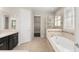 Bright bathroom featuring double vanity, soaking tub, glass enclosed shower, and neutral tile at 970 Timberview Rd, Clermont, FL 34715
